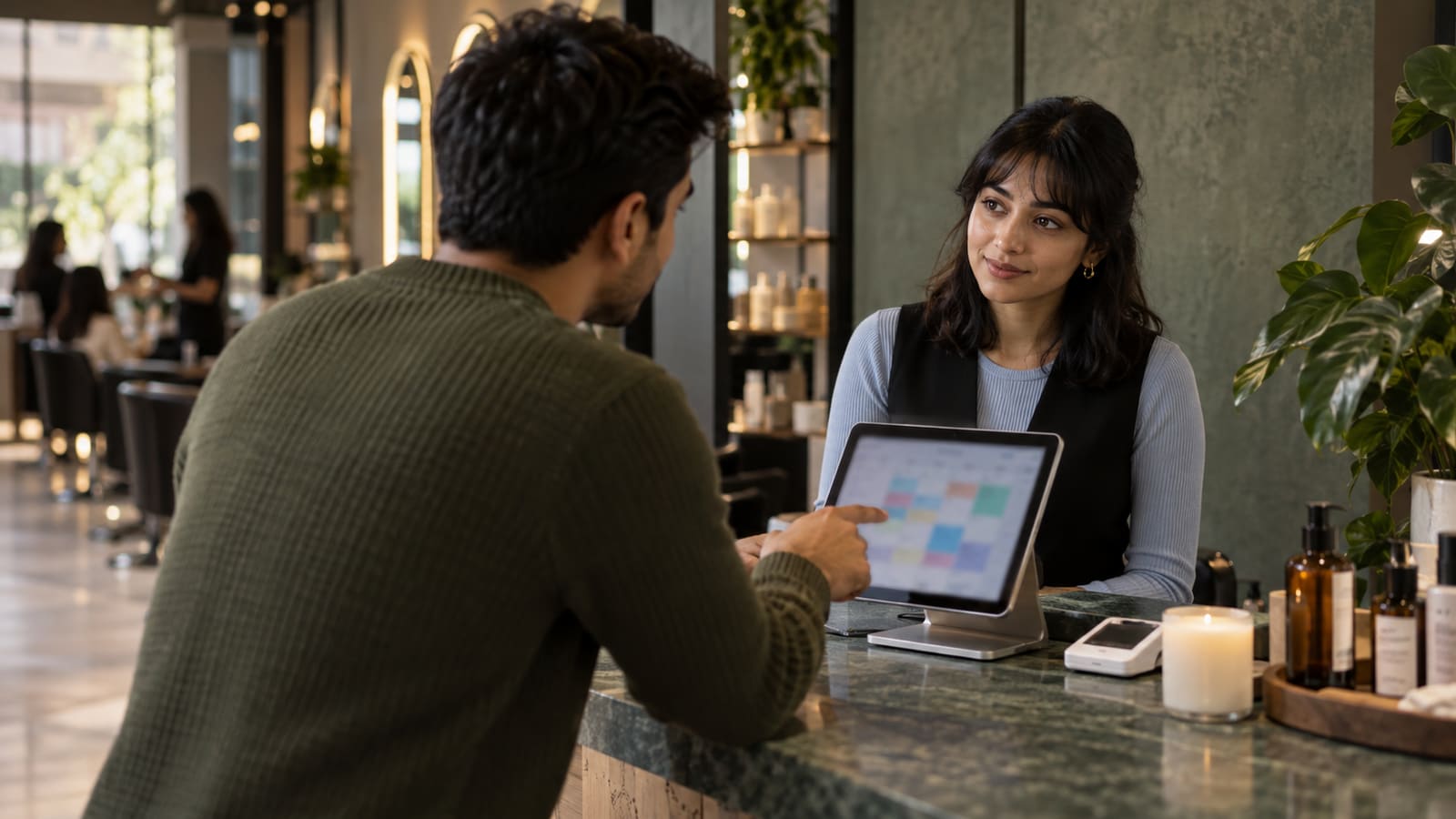 A salon owner showing a customer the day’s schedule on a tablet